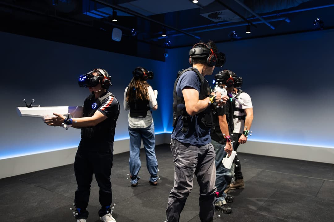A group of players in headsets moving through a blue-lit game room