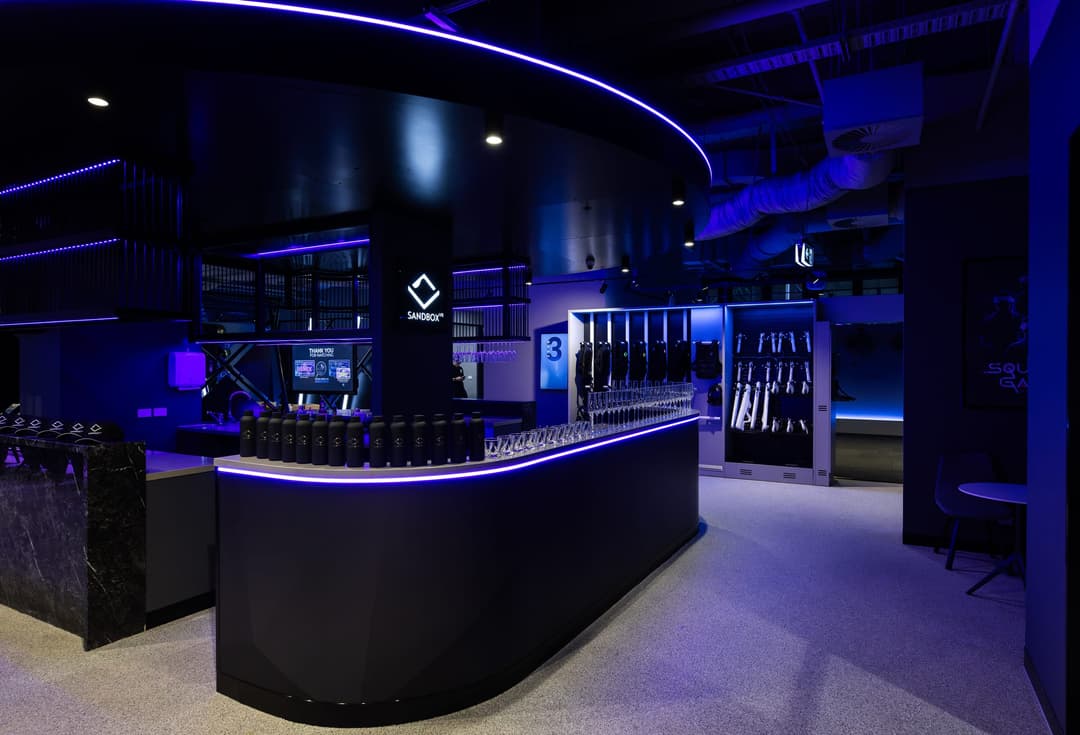 The bar counter under a ring of light, the Sandbox VR mark behind