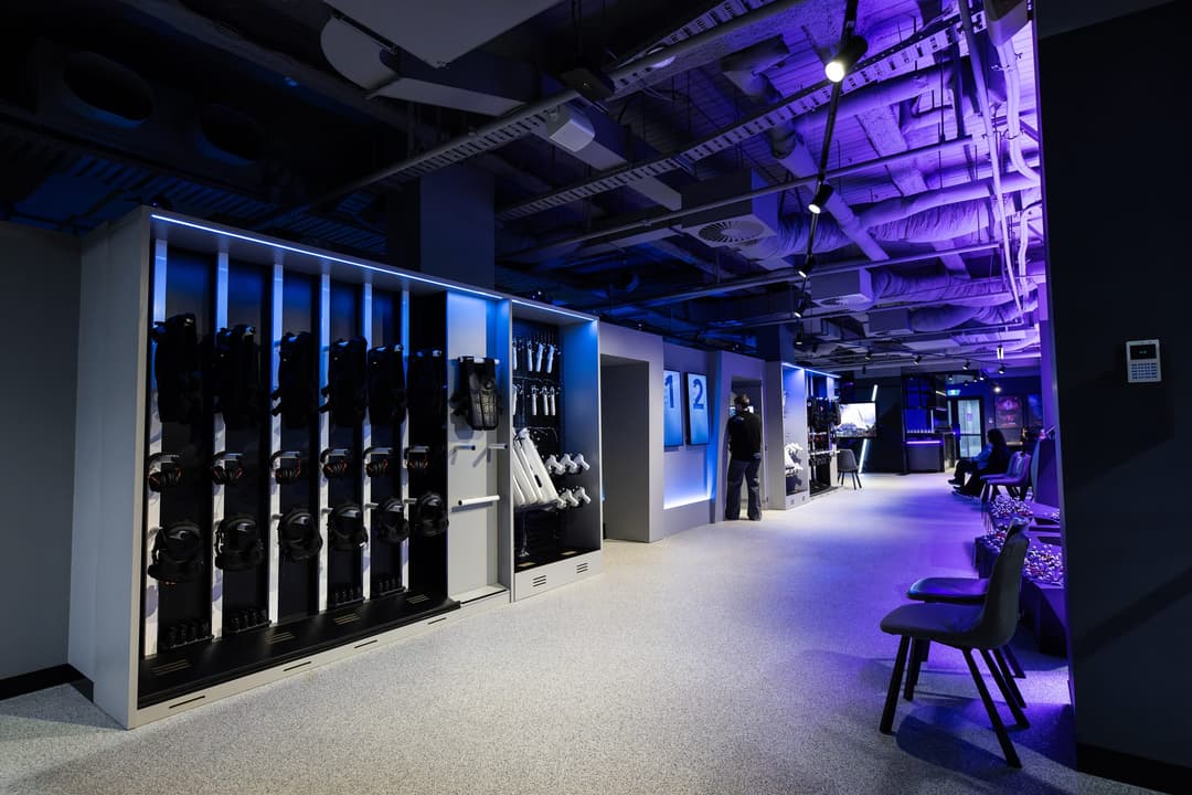 A corridor lined with gear lockers under purple light