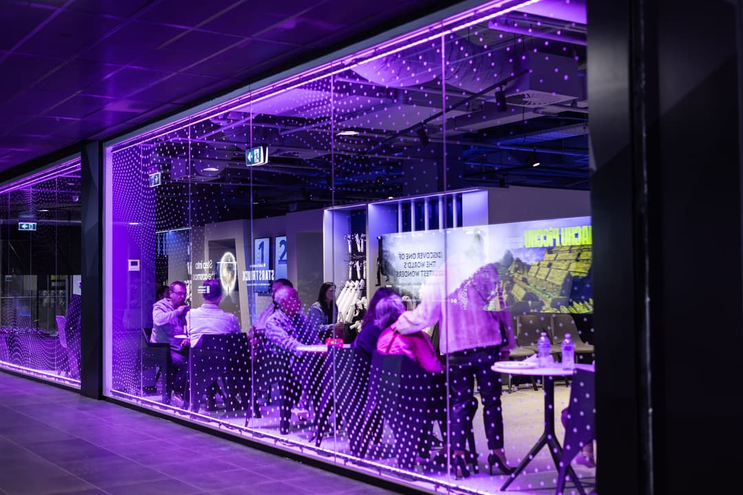 A glass-walled room lit purple, guests inside