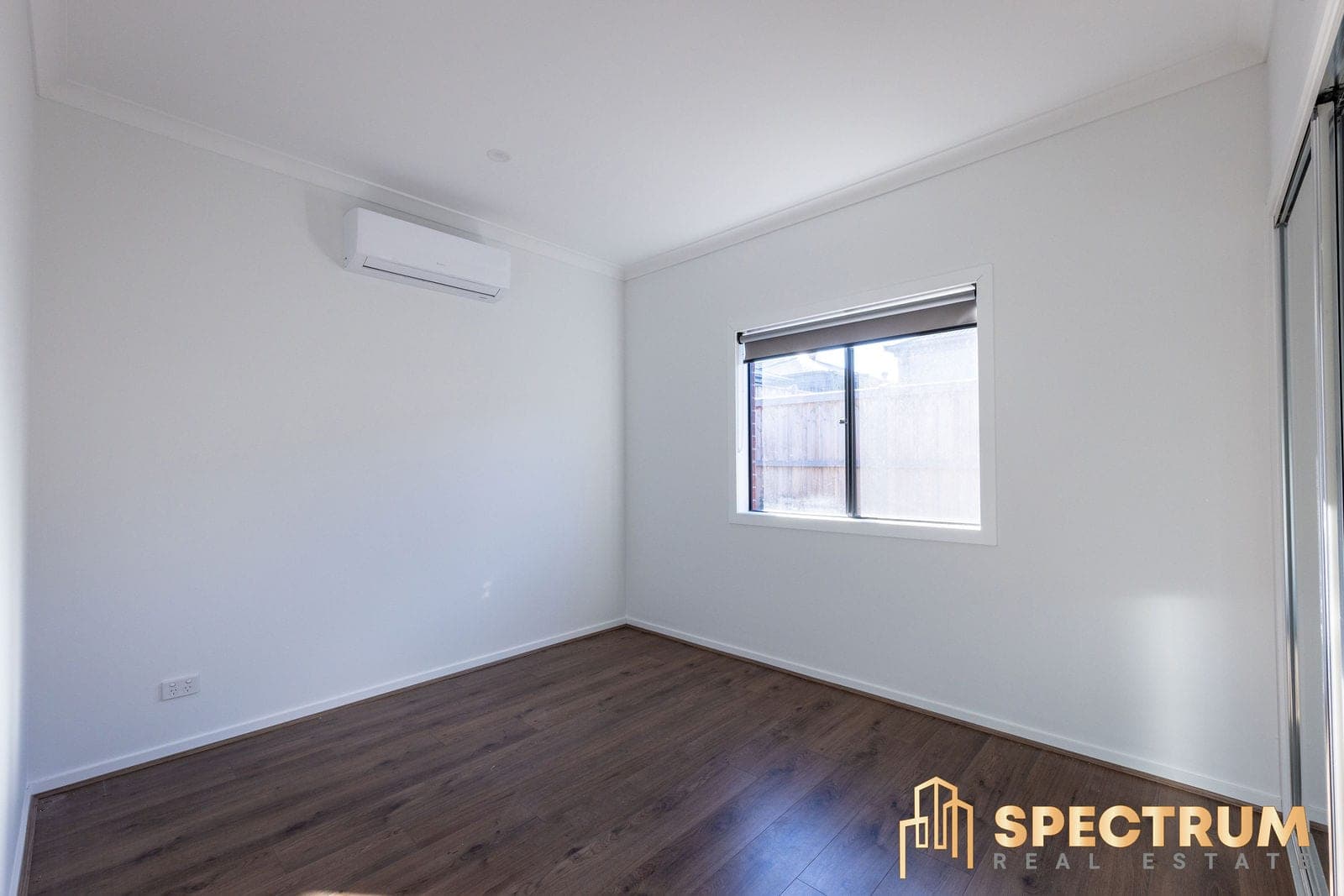 An empty bedroom in a new home, window to the side fence and a built-in robe