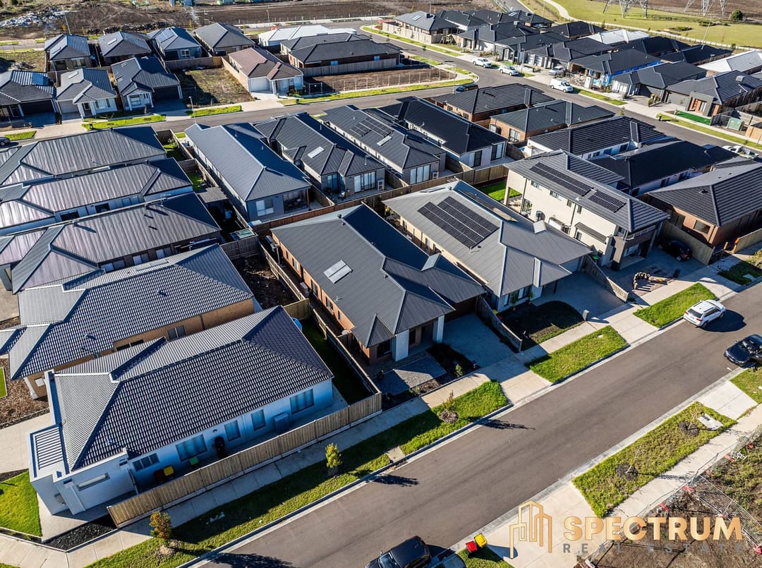 Low drone pass over new homes on a suburban street, solar panels on the roofs