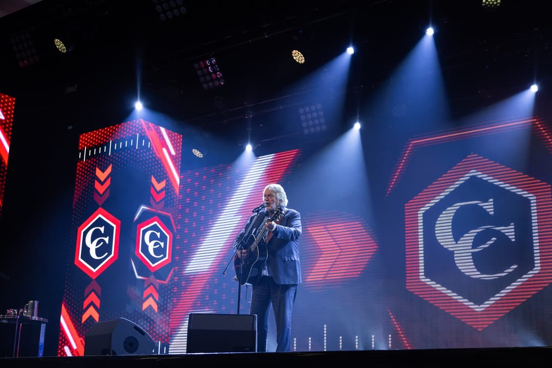 A musician with a guitar alone on the lit stage