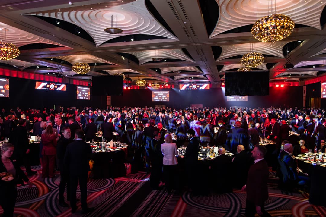 Guests filling the ballroom at round tables under chandeliers