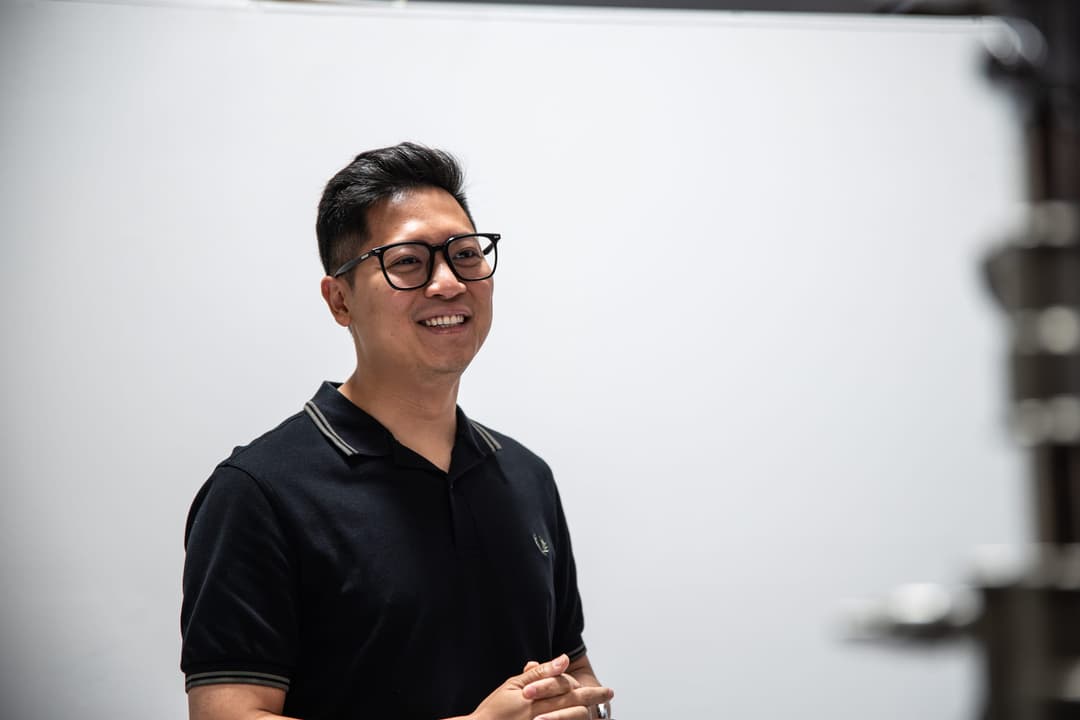 A client in a black polo smiles on the white backdrop.