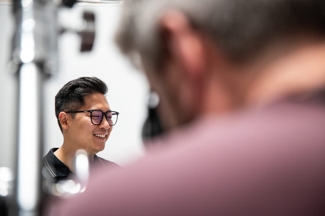 A client in glasses laughs on the white backdrop.