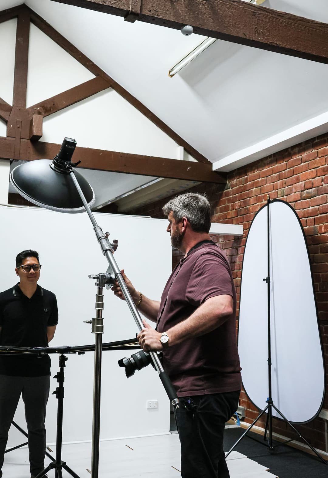 The photographer works a boom light over a client.