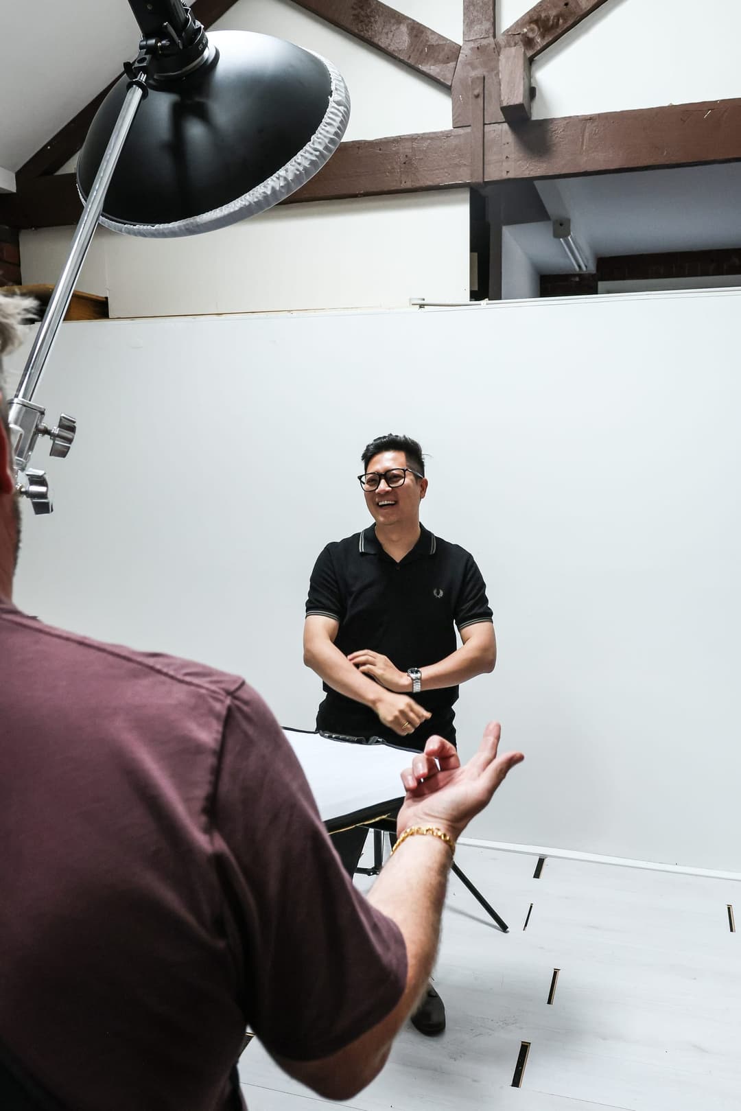 A client sits on the white backdrop while the photographer directs.