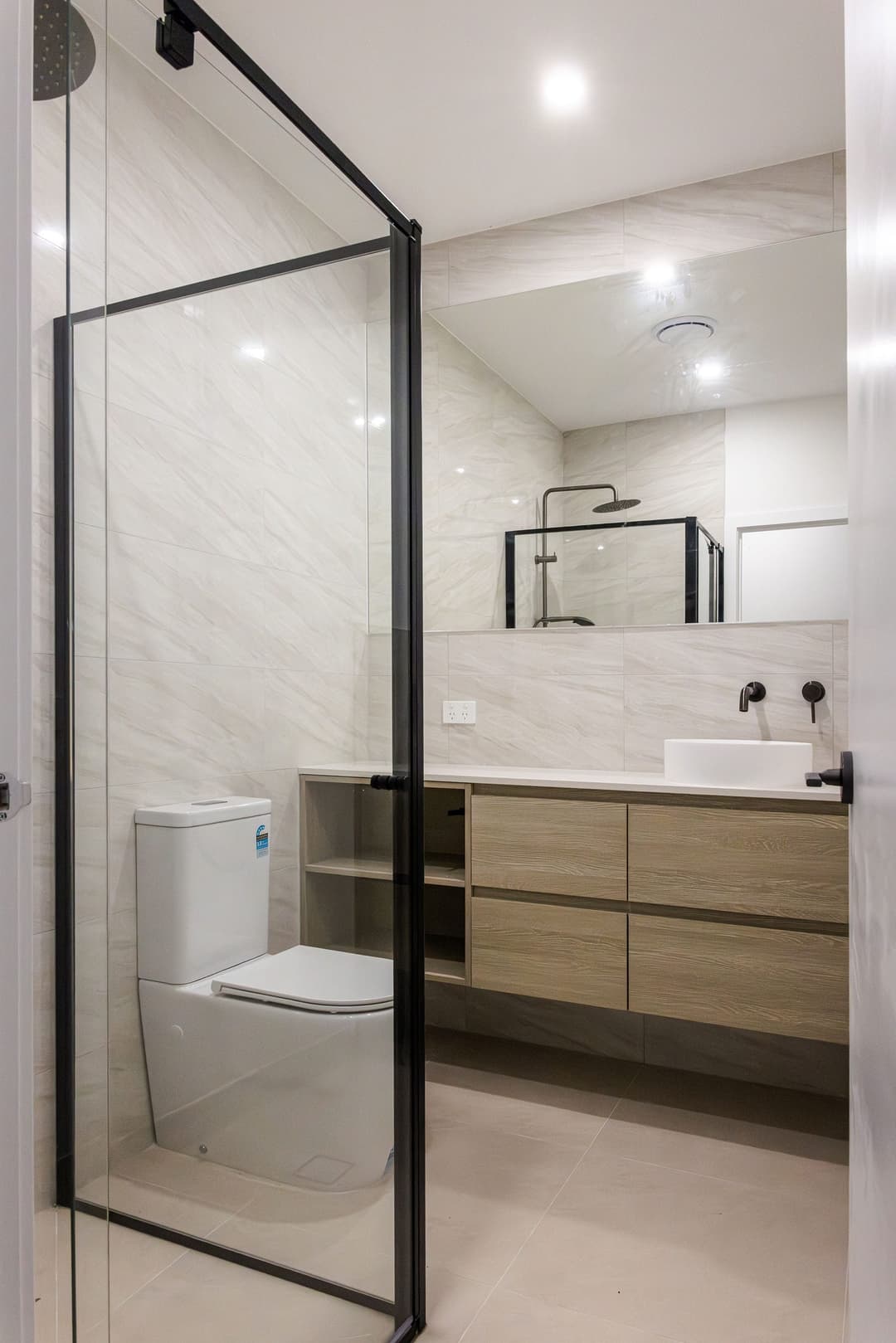 Bathroom with a black-framed shower screen and a timber vanity