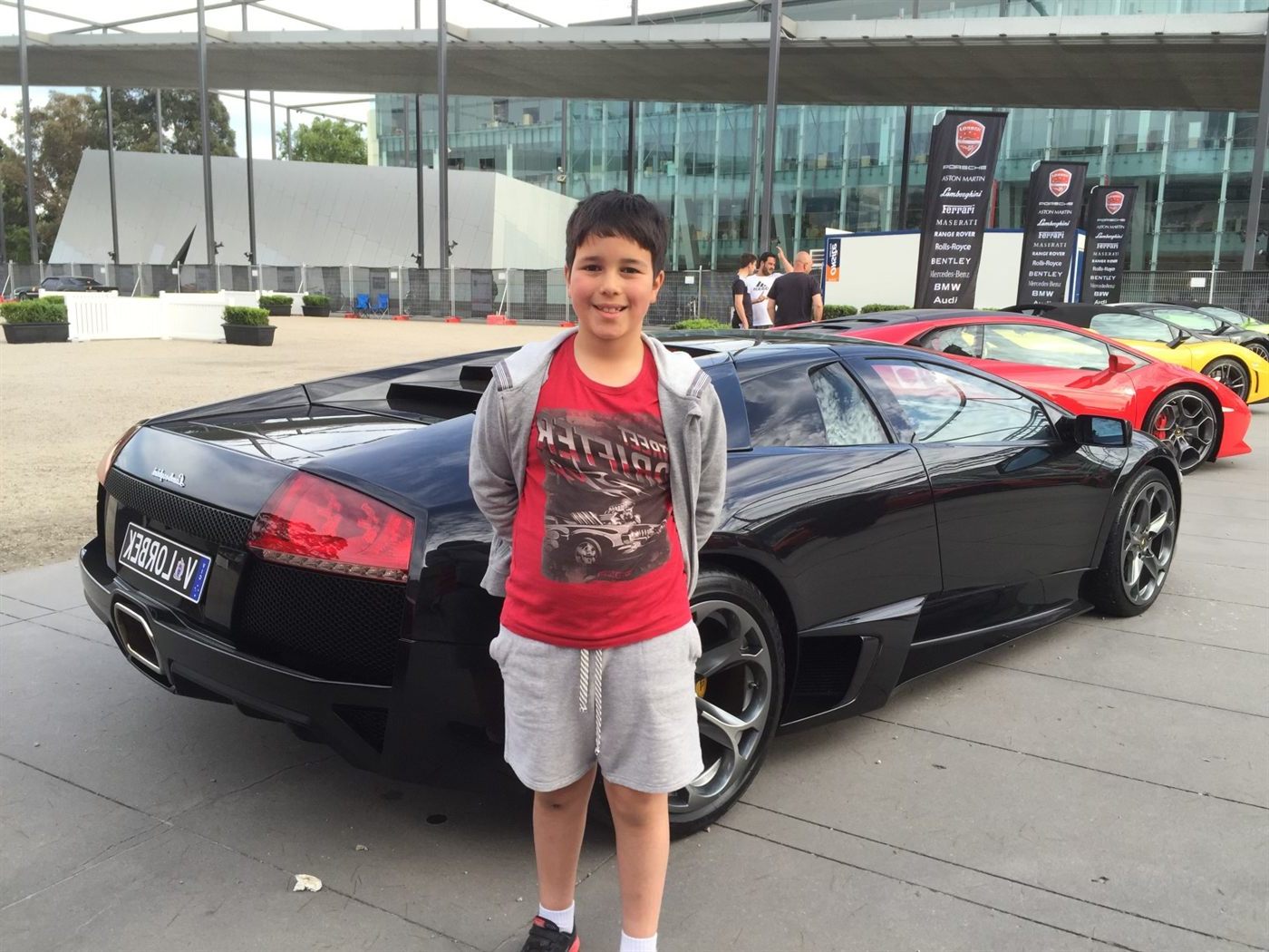 Young Gabe beside a black Lamborghini at a Lorbek car show